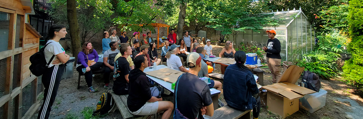 A workshop with instructor and attendees in a community garden.