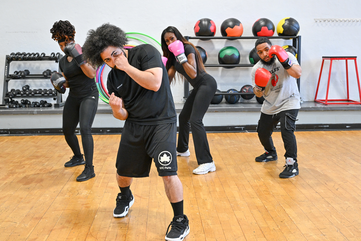 An instructor demonstrates a boxing move while participants with gloves mimic the punching pose.